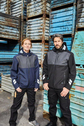 Two models wearing Hardshell Workwear Jackets in navy and black, standing against a backdrop of blue and grey crates.