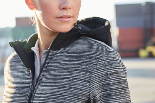 A padded hybrid jacket featuring a black hood and a textured grey body, designed for women. It has a logo on the jacket.