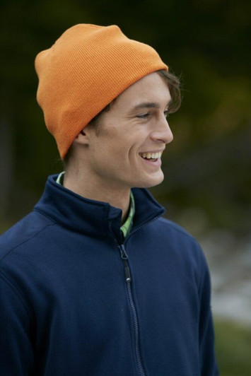 An orange beanie worn by a smiling man dressed in a navy jacket, set against a natural backdrop.