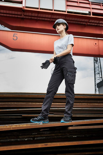 Workwear-Pants light in black, worn by a model in a construction setting, featuring side pockets and a logo.