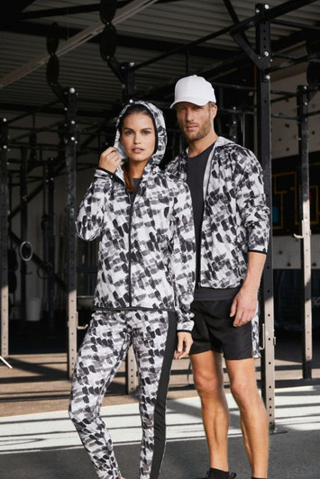 A ladies' soft shell jacket featuring a black and white graphic pattern, accompanied by a male model in matching attire.
