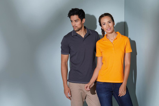 A grey polo shirt and an orange polo shirt are worn by a man and woman standing together in a modern setting.