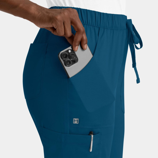 A pair of teal cargo pants with a full elastic waistband and pockets, featuring a hand placing a phone in one pocket.