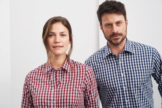A red and white checked shirt on a woman and a blue and white checked shirt on a man, both featuring button-up designs.