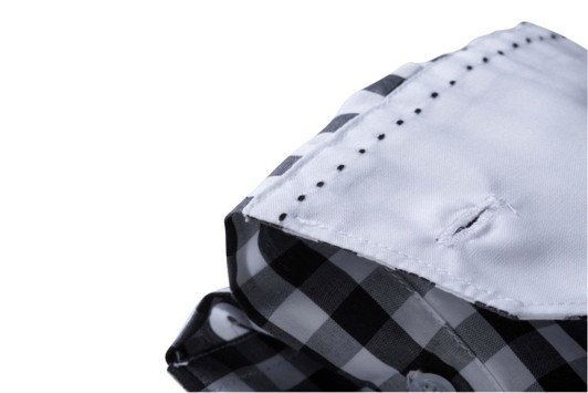 A close-up of a black and white checked button-up shirt collar, featuring a logo and detailed stitching.