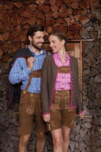 A traditional ladies' button-up shirt in pink and white check, paired with a brown cardigan and lederhosen, against a wooden backdrop.