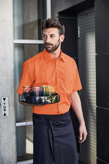 An orange short-sleeved button-up shirt worn by a man holding a tray, standing by a building entrance.