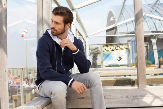 A navy blue men's track jacket with a hood, featuring a two-tone design, displayed in a bright outdoor setting.