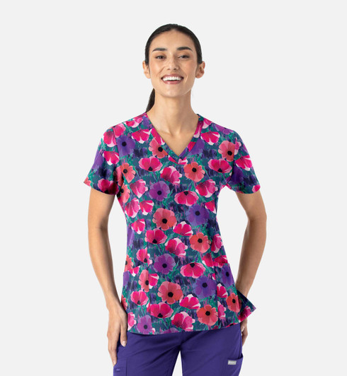 A vibrant women's V-neck top featuring a floral print in purple, pink, and green hues. It includes a logo.