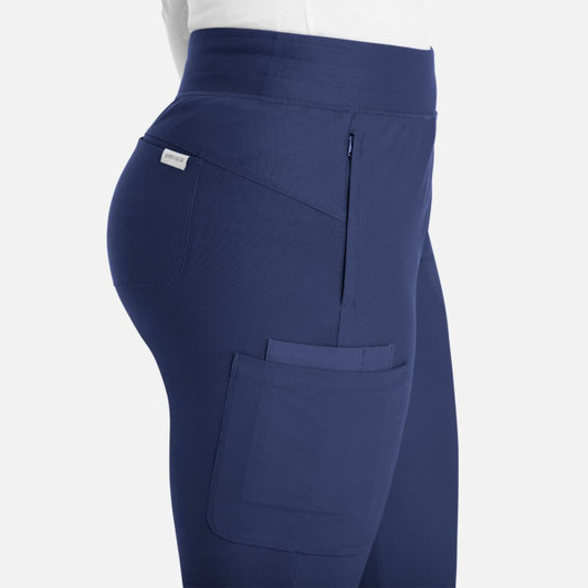 A side view of mid-rise joggers in navy blue, featuring pockets and a branded logo.