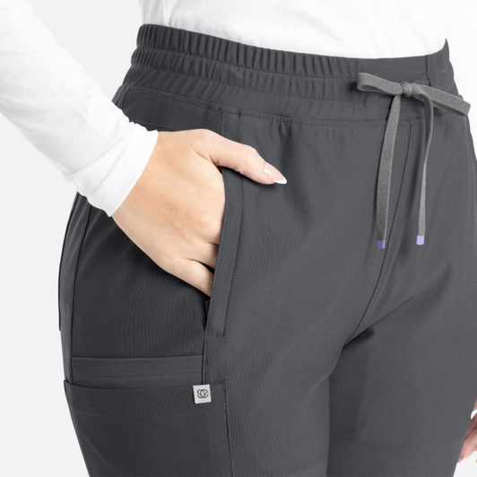A close-up of the Embrace Nora Bootcut Pant in dark grey, featuring an adjustable waistband and side pockets.