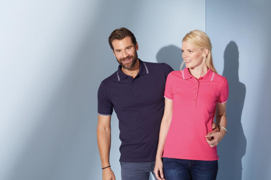 A navy blue polo shirt and a pink polo shirt feature a contrasting collar and are worn by a man and a woman.