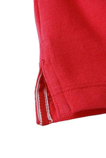 A close-up of a red polo shirt, featuring a textured fabric and a small side vent detail.