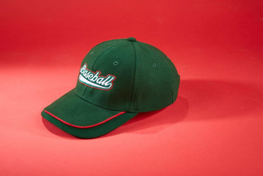 A green cap with a curved peak and a logo, featuring red accents on the brim.