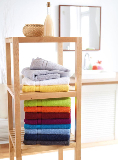 A display of neatly stacked bath towels in various colours, including grey, yellow, red, and blue, on a wooden shelf.