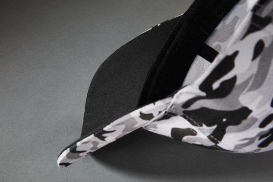 A 6-panel camouflage cap featuring a grey and black pattern and a black underside on the brim.