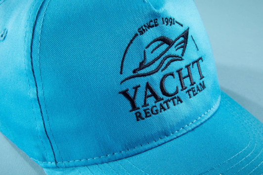A light blue 5 panel cap made of organic cotton featuring a logo embroidered on the front.