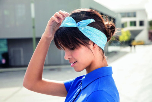 A woman wearing a light blue bandana styled as a headband, showcasing a tied bow.