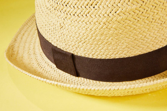 A straw hat in a natural beige colour with a dark brown band around the base.