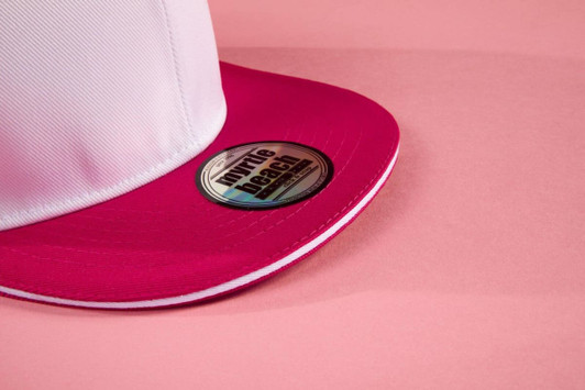 A pink and white trucker cap featuring a circular logo on the brim.
