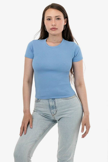 A model wearing a fitted light blue baby rib t-shirt paired with light jeans, with a minimalistic background.