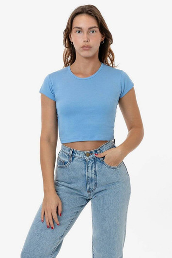 A light blue cap sleeve crop top paired with high-waisted jeans. The top has minimalistic styling and a logo.