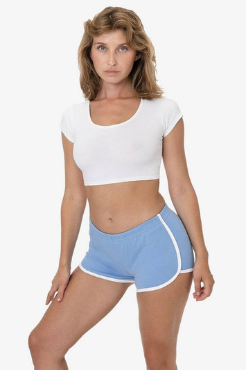 Interlock running shorts in light blue with white trim, paired with a white crop top. The model is standing confidently.