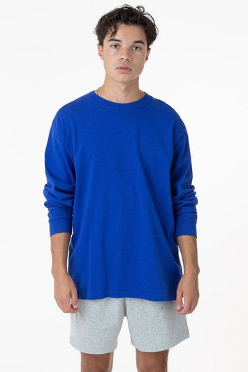 A long sleeve crewneck tee in bright blue, featuring a relaxed fit. The model wears grey shorts.