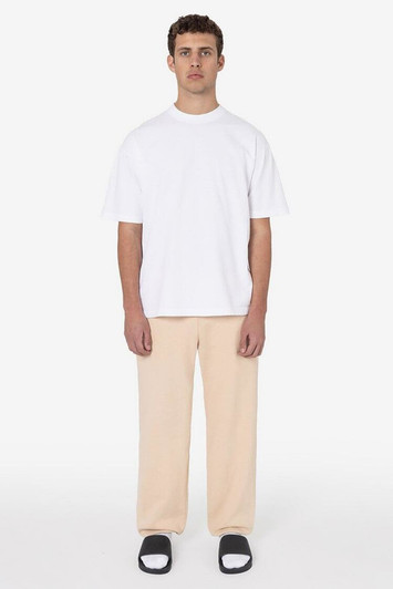 A man wears a casual white t-shirt and beige heavy fleece sweatpants, paired with black and white slide sandals.