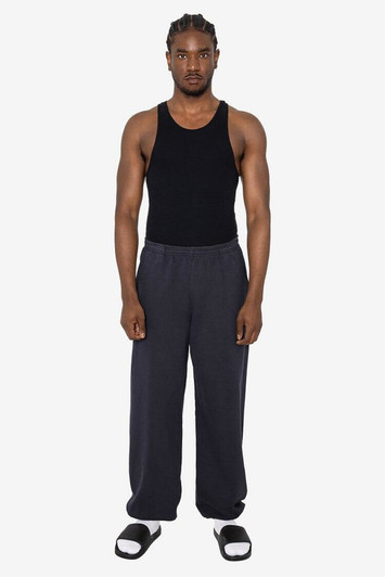 A pair of heavy fleece sweatpants in dark grey, worn by a model with a black tank top and sandals.