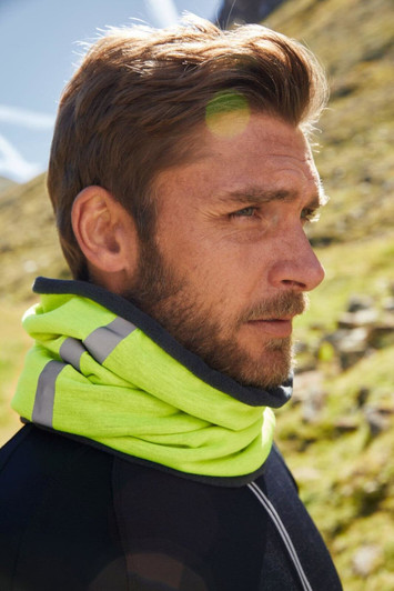 A bright yellow scarf with grey accents is worn around a man's neck against a natural backdrop.