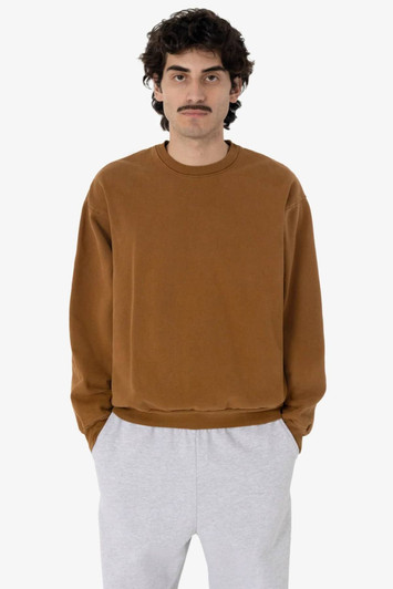 A man wears a brown heavy fleece pullover paired with grey sweatpants. The pullover has a simple design and logo.