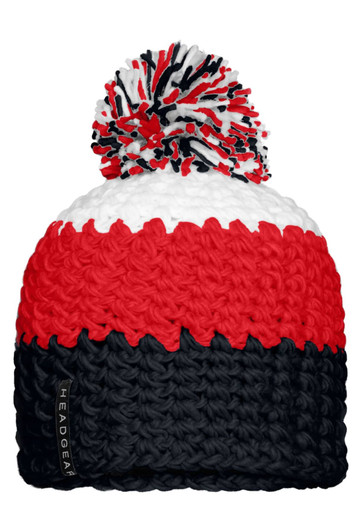 A knitted beanie in red, white and navy blue, featuring a large pompon on top and a logo on the side.