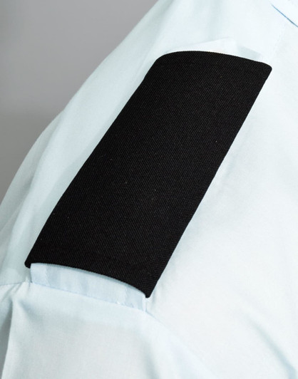 A light blue shirt with a black fabric epaulette on the sleeve, featuring a solid black section.