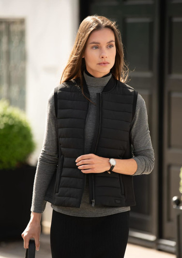 A black women's vest with a quilted design, worn over a grey turtleneck, set against a stylish background.