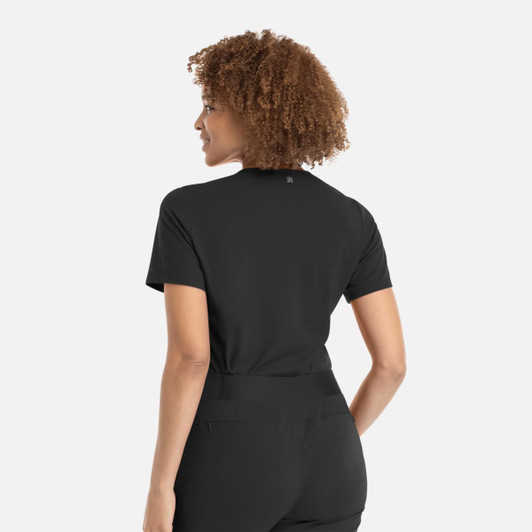 A woman with curly hair wearing a black banded V-neck top, viewed from the back. The top features a logo.
