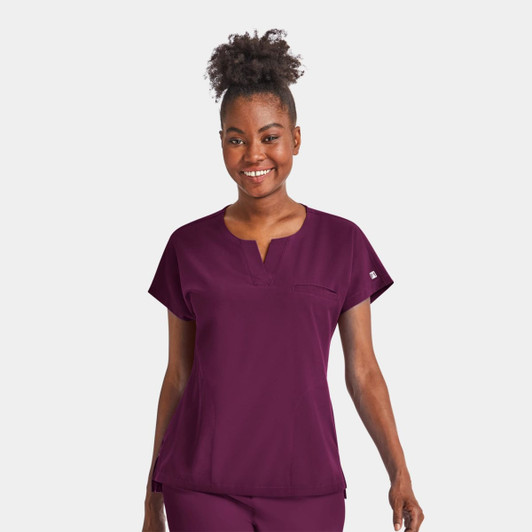 A women's notched neck dolman top in burgundy, featuring short sleeves and a chest pocket. The top has a logo.