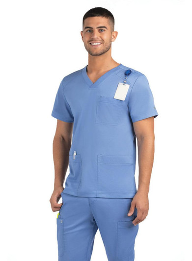 A man wearing a blue V-neck top with three pockets, featuring a logo and a tag.