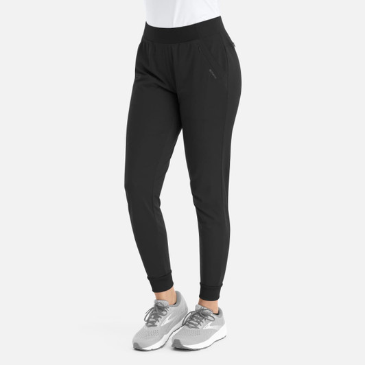 Mid-rise elastic jogger in black, featuring a tapered fit and a logo. Paired with grey athletic shoes.