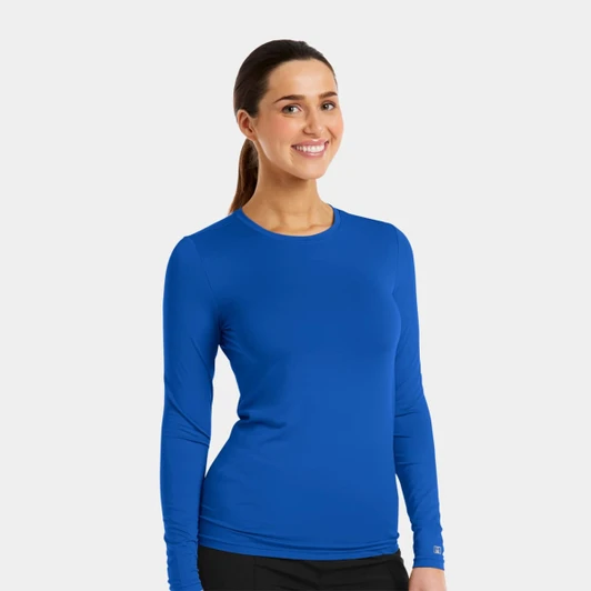 A woman wearing a long-sleeve, bright blue underscrub tee with a fitted design and a logo.