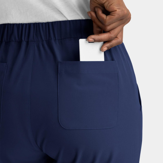 A close-up of a person's back pocket featuring a white card being inserted into navy blue pull-on pants.