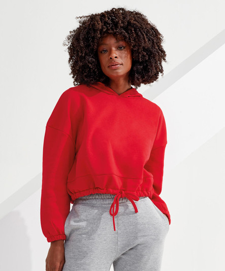 A red cropped oversize hoodie with a drawstring hood, paired with grey pants, featuring a logo on the fabric.