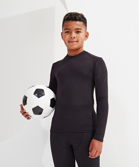 A boy stands holding a black and white soccer ball, wearing a fitted black performance baselayer with long sleeves.