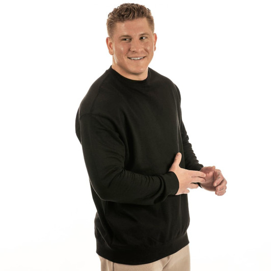 A black pullover crewneck sweatshirt worn by a smiling man. The sweatshirt features a simple design and has a logo.
