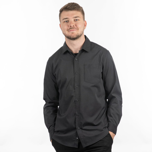 A man wearing a black Stretched Poplin Shirt with a button-up front and a pocket. The shirt has a subtle logo.