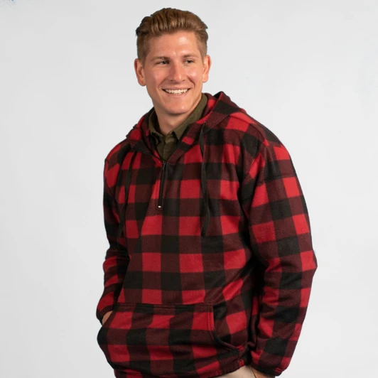 A red and black checkered 1/4 zip polar fleece hoodie worn by a smiling man. Features a front pocket and a logo.