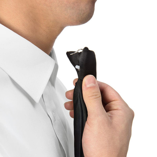 A person holding a black Clip Tie near their neck, wearing a white shirt. The product features a logo.