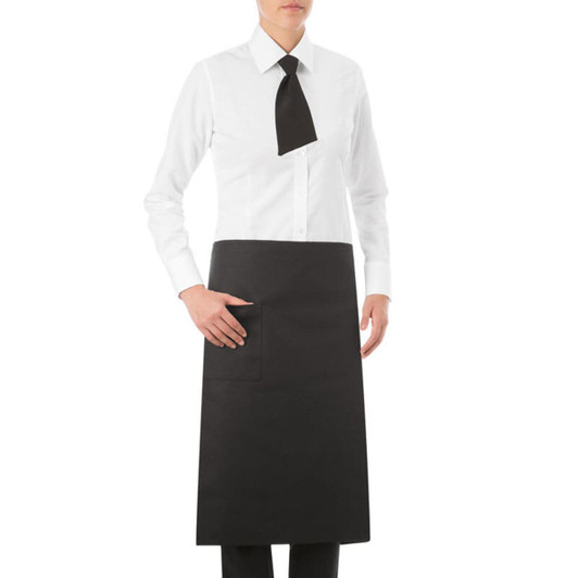 A black apron worn over a white shirt, featuring a pocket and a black tie. The model stands with one hand on the pocket.