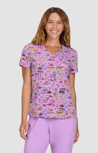 A purple printed top featuring a playful pattern, with a V-neckline and short sleeves. The model is smiling.