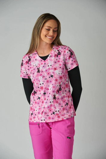 A pink scrubs top featuring a floral and bunny pattern, paired with a black long-sleeve underneath and pink pants.